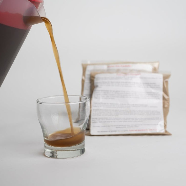 pouring essiac from a pitcher into a cup with two packets of herbs